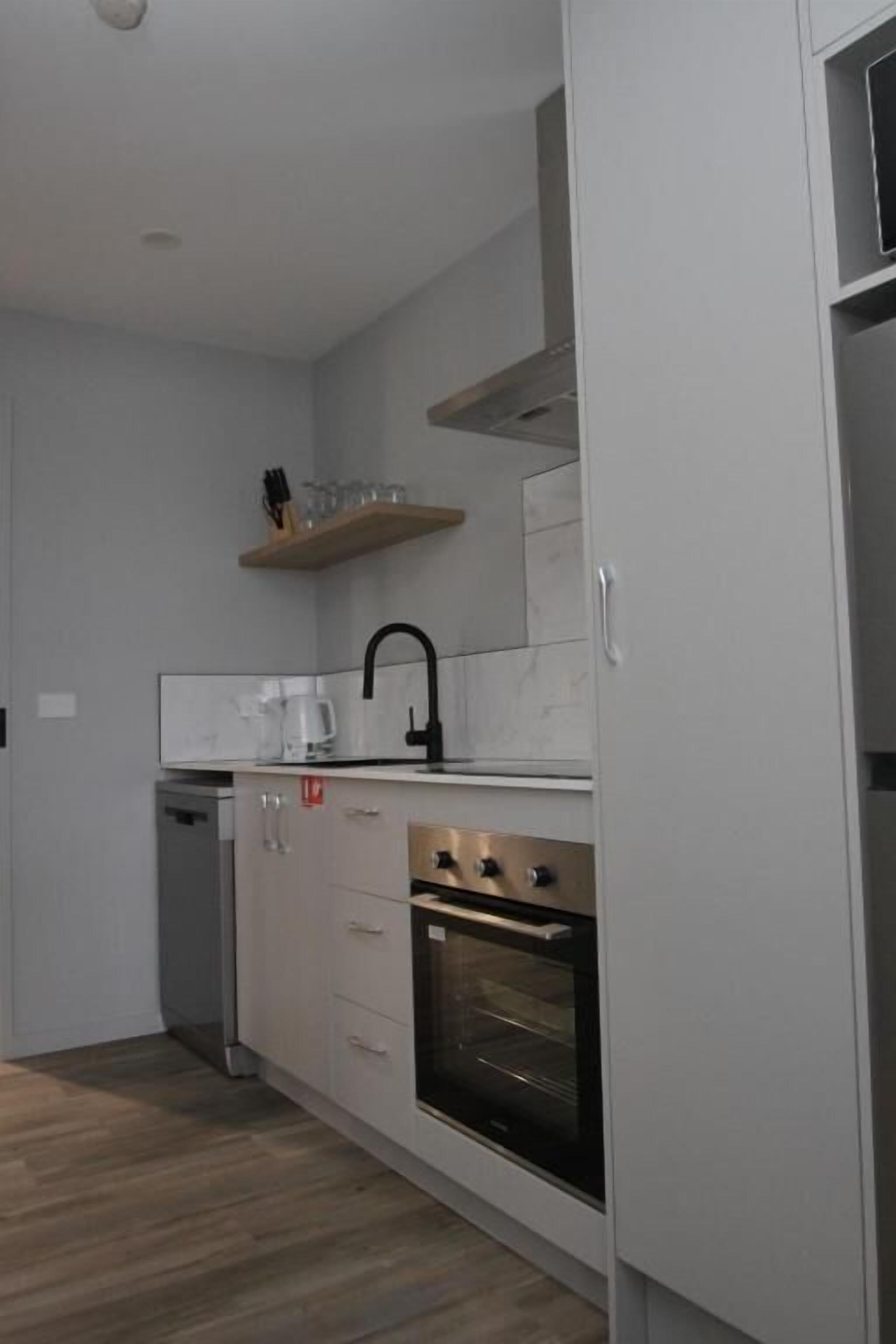 Una cucina con mobili bianchi, forno integrato e macchina da caffè.