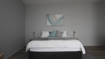 A bedroom with a bed, pillows, a blanket, a bedside table, and a wall-mounted lamp.