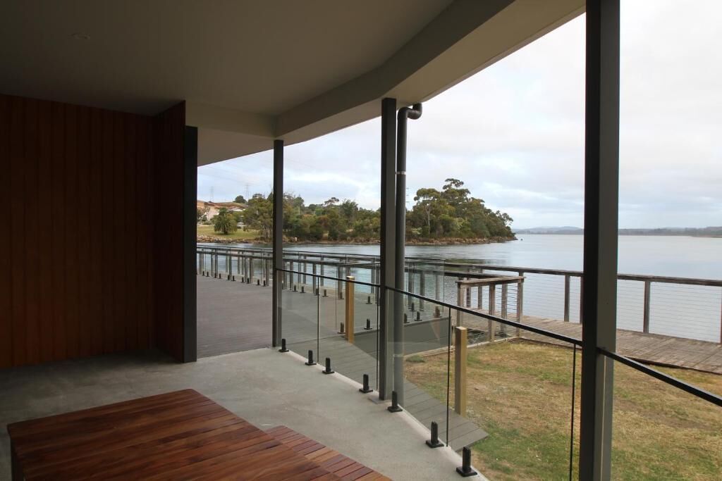 A modern interior with a view of a lake and a wooden deck outside.