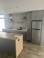 Una cocina moderna con gabinetes grises, un refrigerador de acero inoxidable y una isla de madera.