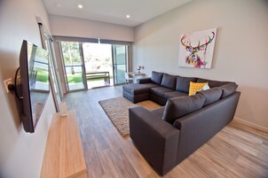 Una sala de estar moderna con un sofá modular, un televisor de pantalla plana y un ventanal con vistas al exterior.