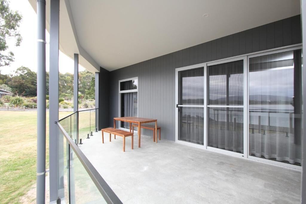 A balcony with a glass railing, a wooden table, and chairs.