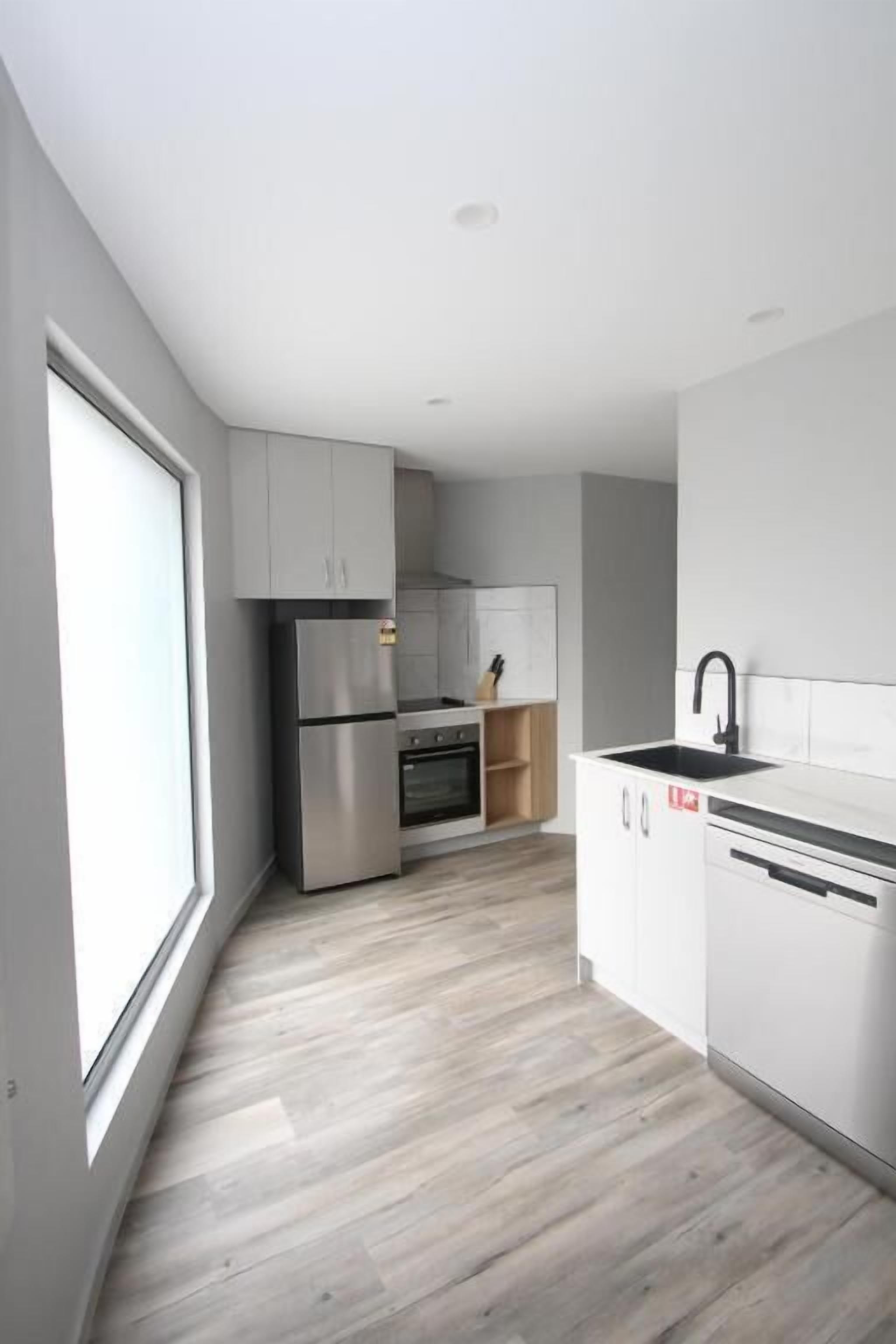 A modern kitchen with white cabinetry, a stainless steel refrigerator, and a dishwasher.