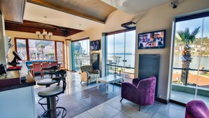 Una habitación amplia con un ventanal grande, una zona de bar y un espacio de estar con vista al mar.
