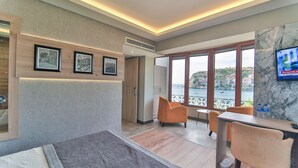Una habitación de hotel moderna con cama, escritorio con silla, televisión y balcón con vistas a la ciudad.