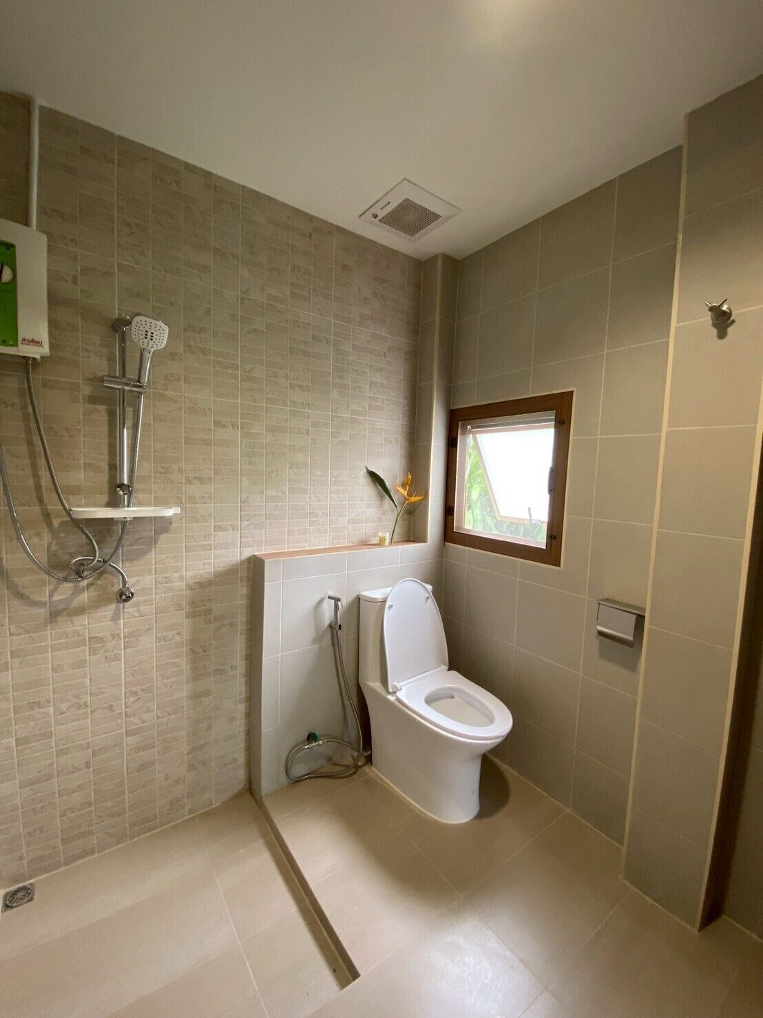 Un baño con inodoro, ducha y ventana.