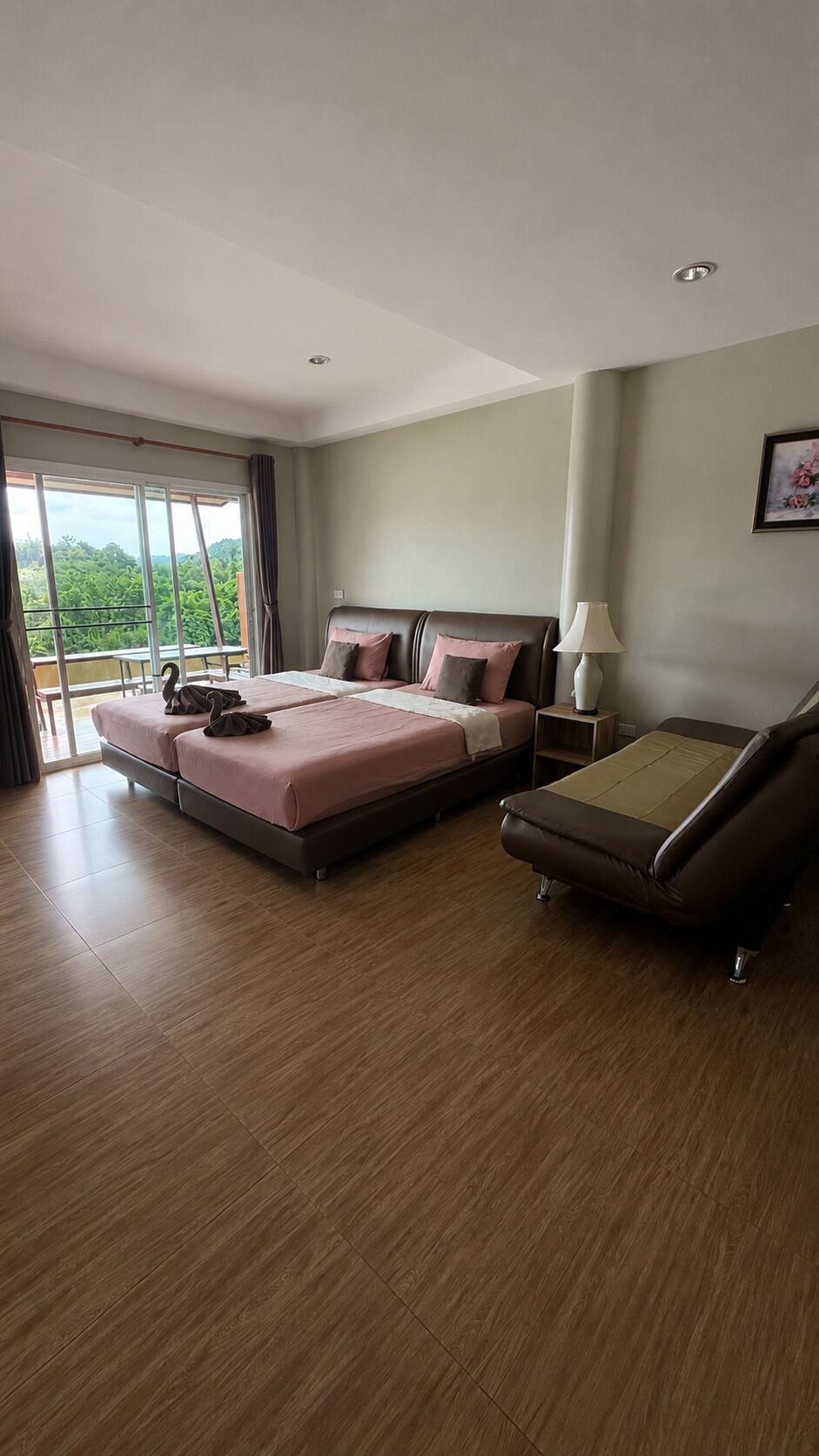 Een hotelkamer met een groot bed, een bank en een balkon met uitzicht.