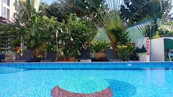Relax by the serene pool surrounded by lush tropical plants and a distinctive circular pattern.