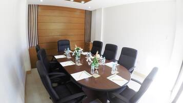 A conference room with a wooden panel wall, a round table, and six black office chairs.