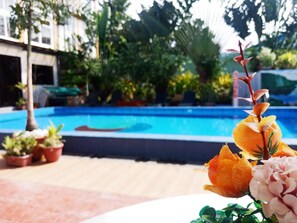 A pool area with a clear view of the pool, surrounded by potted plants and a building in the background. - Aerostop Hotel & Restaurant (Plaridel)