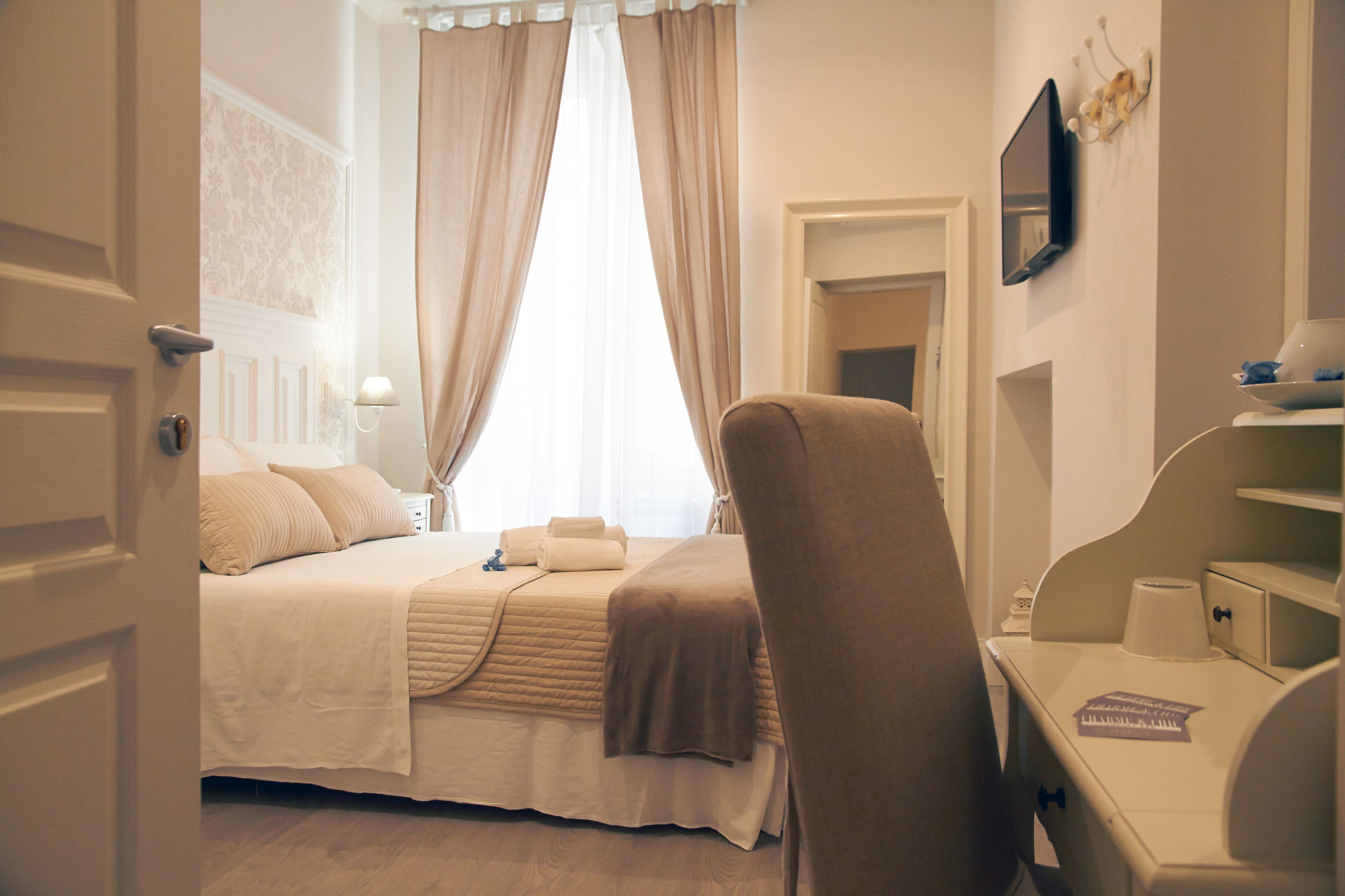 A hotel room with a bed, a chair, a desk, and a TV.