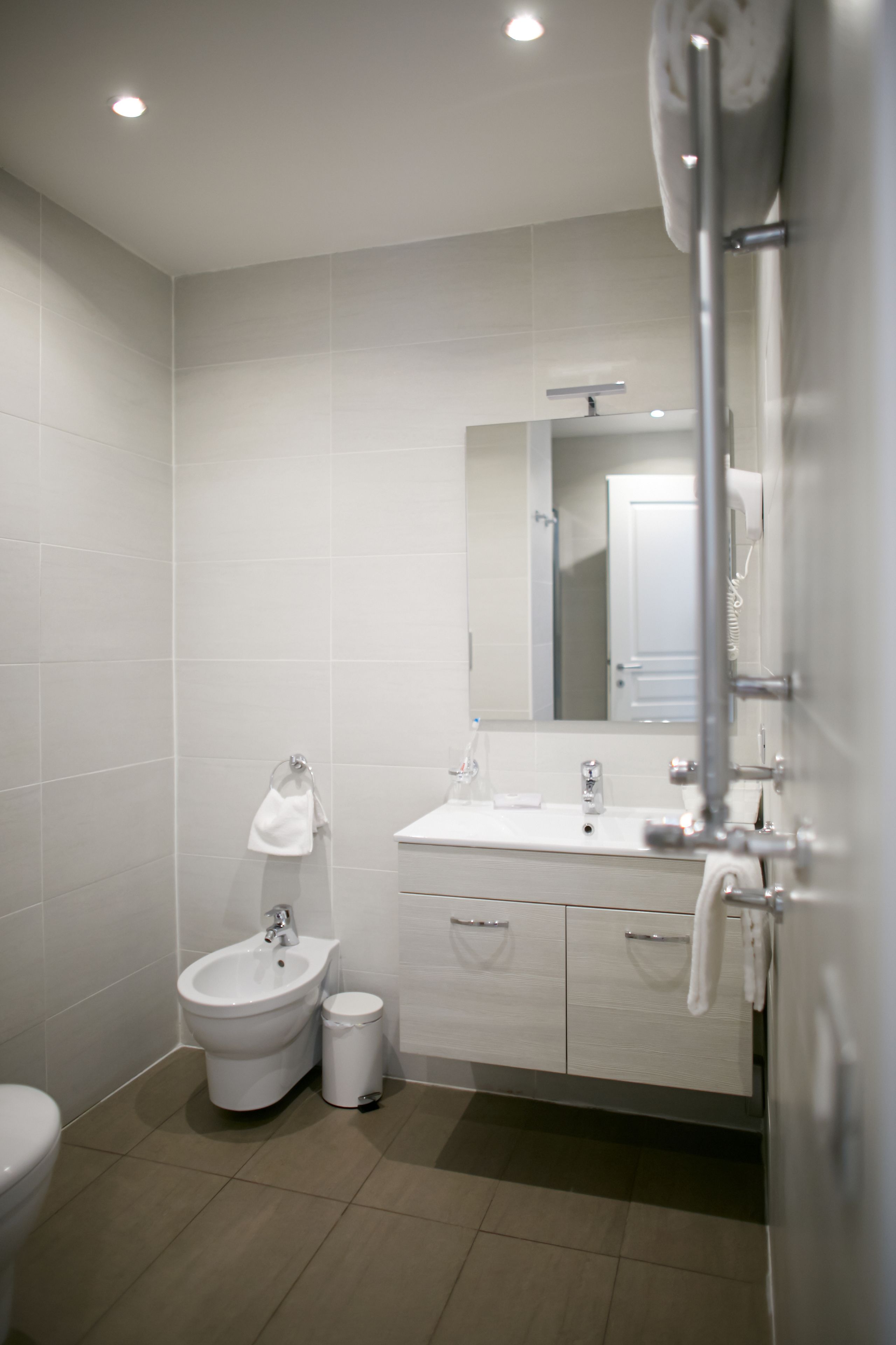 A modern bathroom with a bidet, sink, mirror, and storage cabinet.