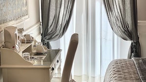 Une chambre avec un lit, un bureau et une chaise. Il y a des rideaux aux fenêtres.