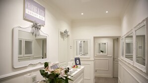Une salle de bain luxueuse, dotée d’une coiffeuse, de grands miroirs et d’une enseigne indiquant : « Charme & Chic, chambre d’hôtes de luxe ».