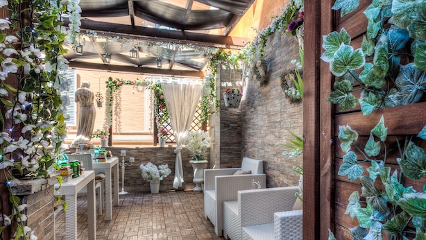 Une terrasse extérieure avec des meubles en osier, un sol en briques et des plantes décoratives.