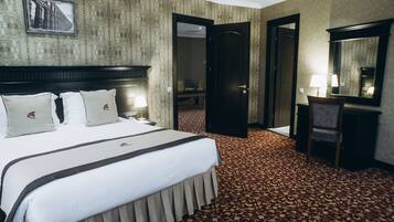 A hotel room with a large bed, a desk, a chair, a mirror, and a carpeted floor.