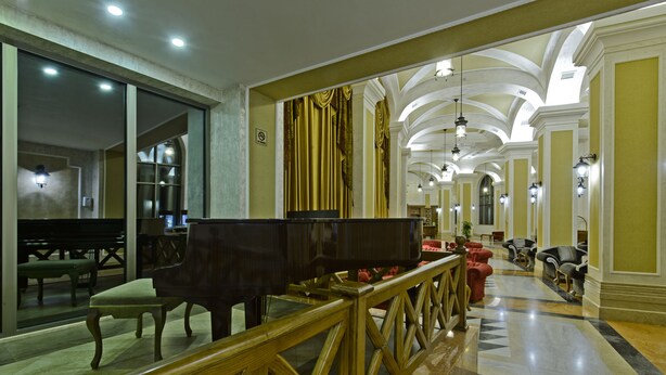 A grand lobby with a grand piano, seating areas, and a marble floor. - Colosseum Marina Hotel (Batumi)