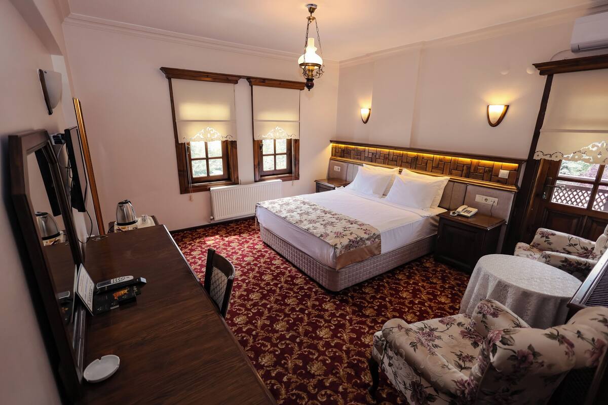Une chambre d’hôtel comprenant un lit, un bureau, une chaise, une petite table et un miroir.