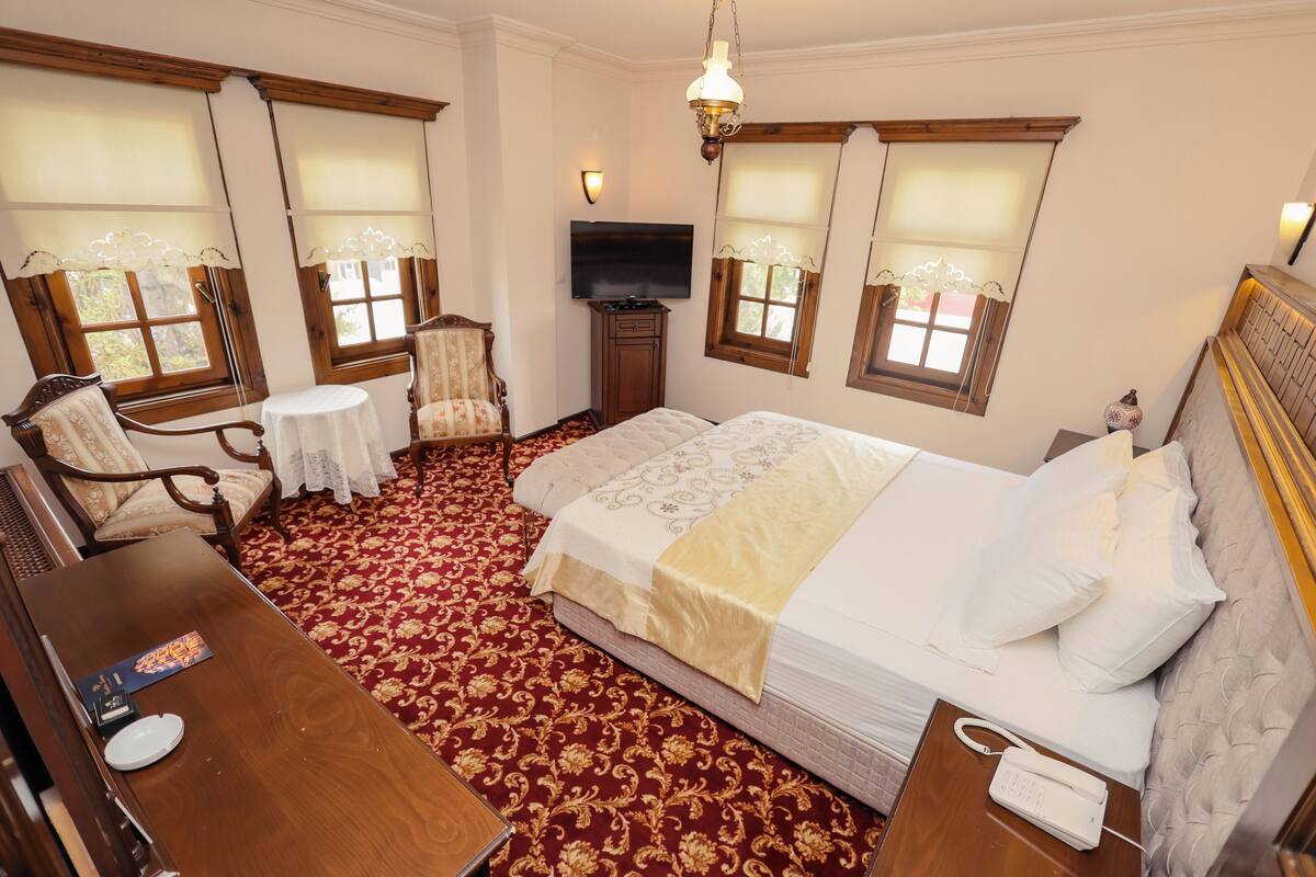 Une chambre d’hôtel avec un grand lit, un bureau, une chaise, une petite table et un téléviseur.