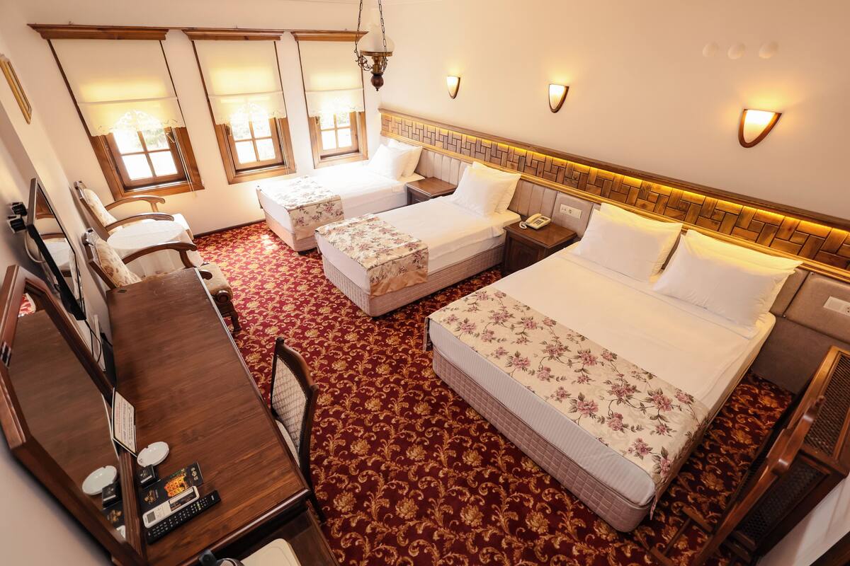 Une chambre d’hôtel avec deux lits simples, un bureau avec un téléphone et un miroir.