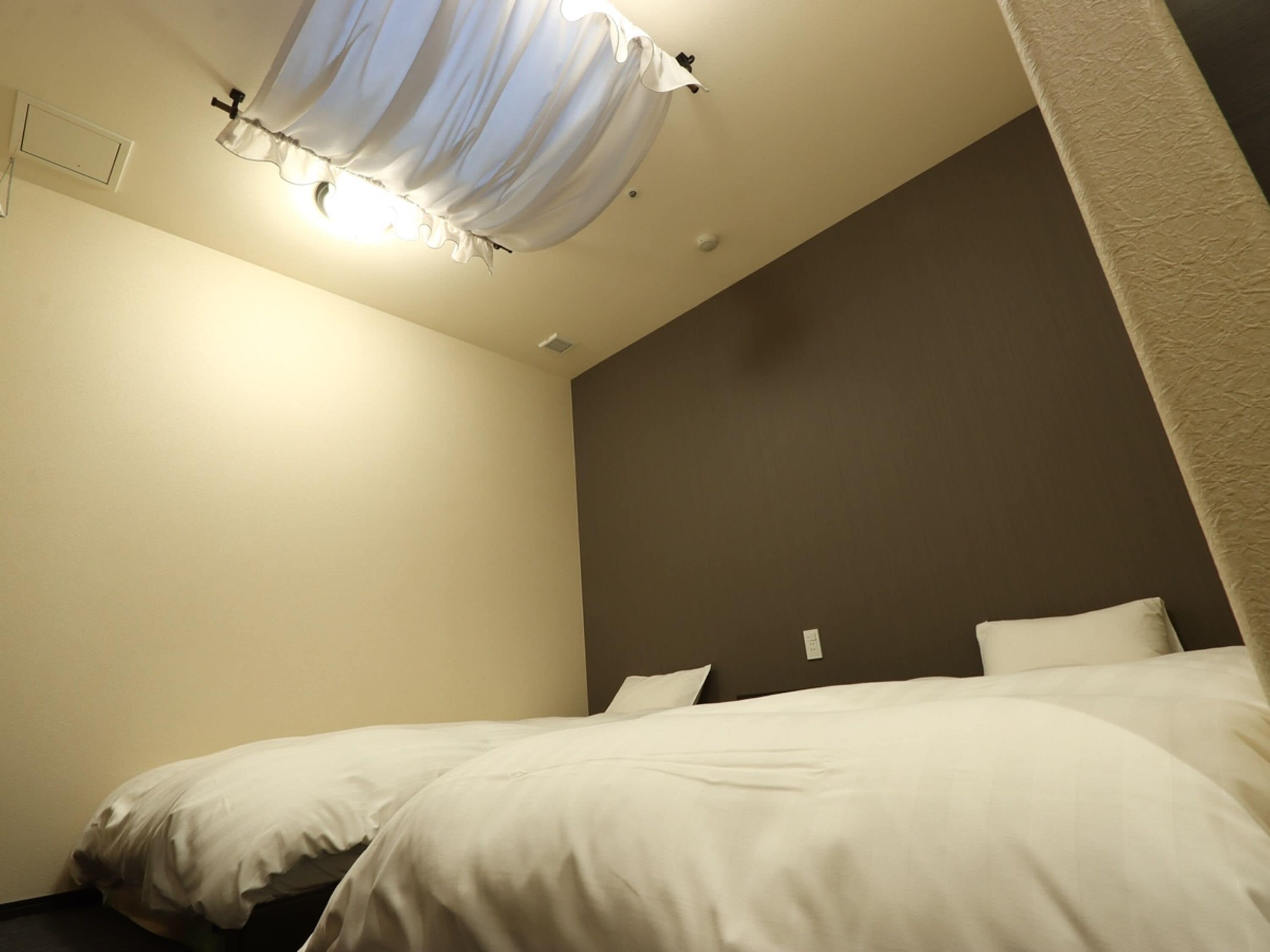 Una habitación de hotel con cama, lámpara de techo y un interruptor de luz en la pared.