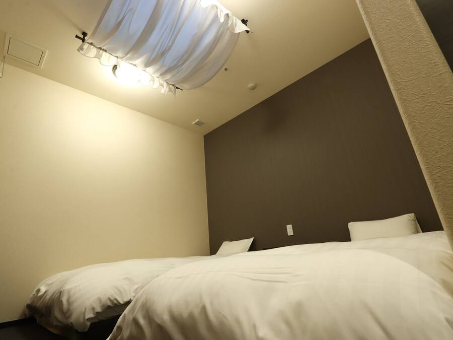 Una habitación de hotel con cama, lámpara de techo y un interruptor de luz en la pared.
