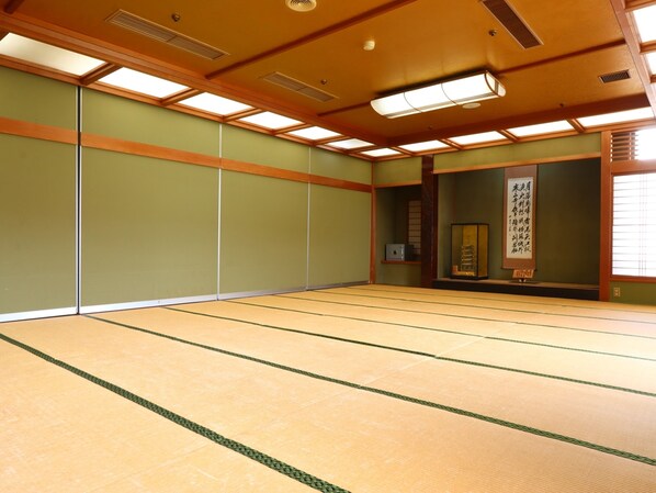 Una habitación con esteras de tatami, techo bajo, vigas de madera y un celosía shoji.