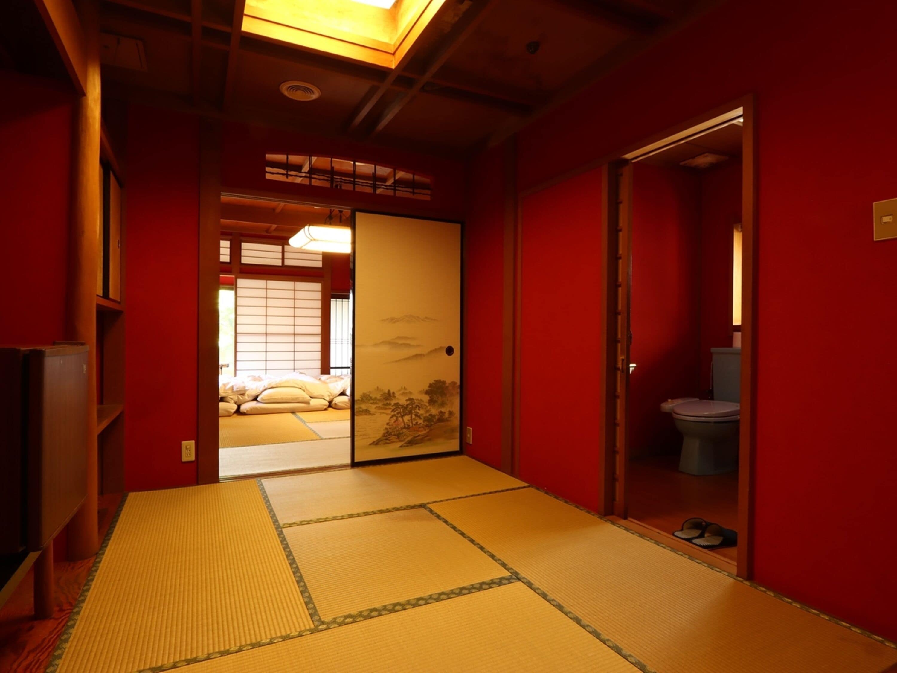 A traditional Japanese room with tatami flooring, a sliding door leading to a bedroom, and a small bathroom.