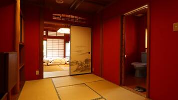 A traditional Japanese room with tatami flooring, a sliding door leading to a bedroom, and a small bathroom.