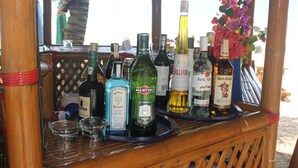 Una zona de bar con diferentes botellas de alcohol y vasos sobre una barra de madera.