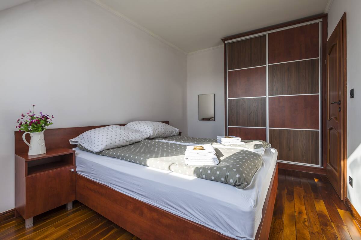 Une chambre à coucher avec un lit en bois, une table de chevet, un miroir et une armoire.