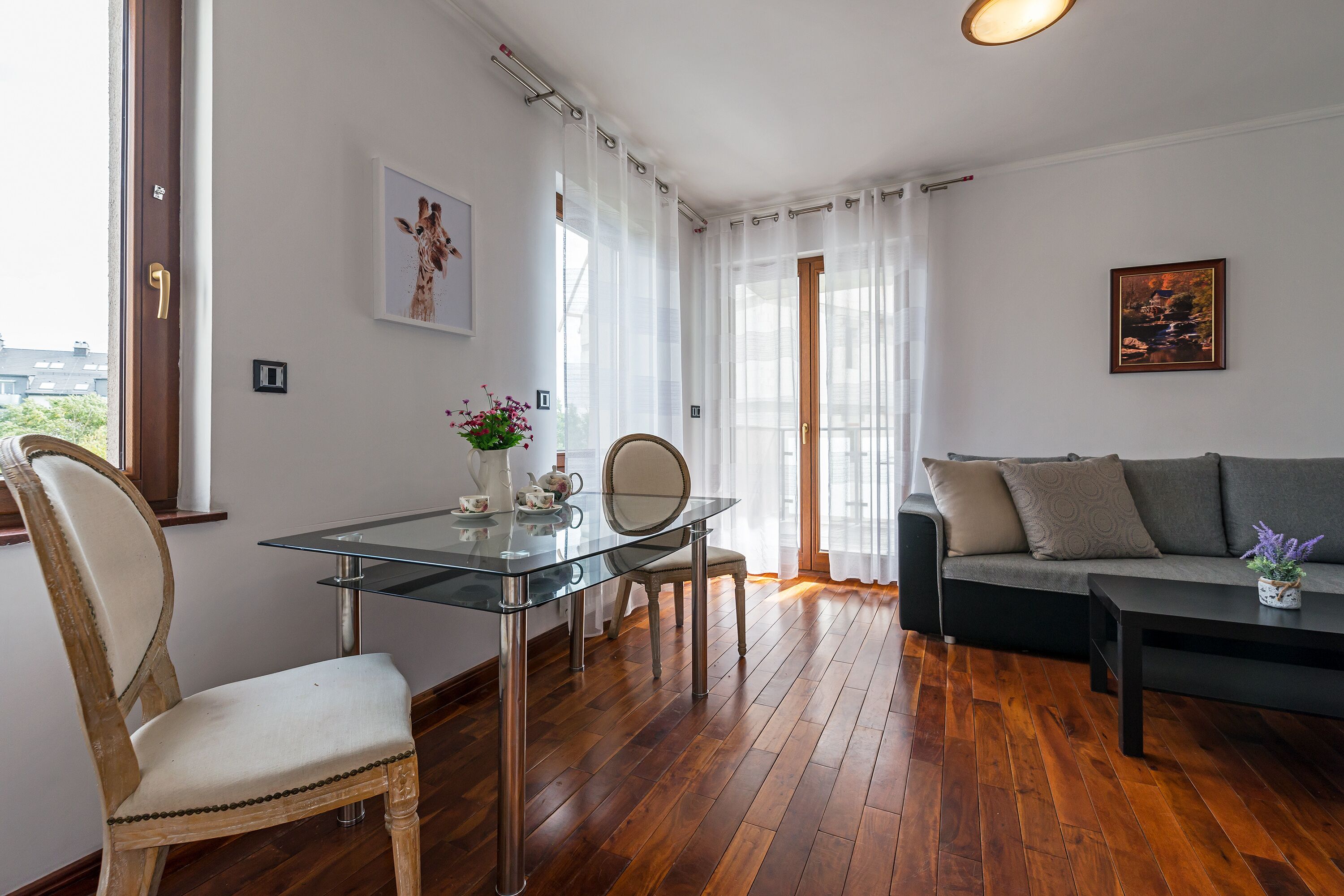 Ein modernes Wohnzimmer mit einem Glastisch, einer Couch und einem Holzboden.
