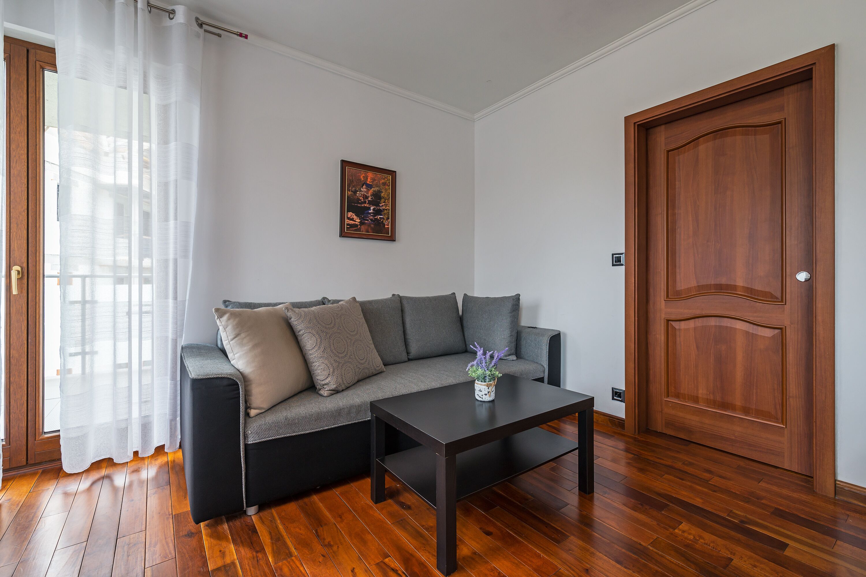 Ein modernes Wohnzimmer mit einem dunkelbraunen Sofa, einem Holztisch und einer Holztür.