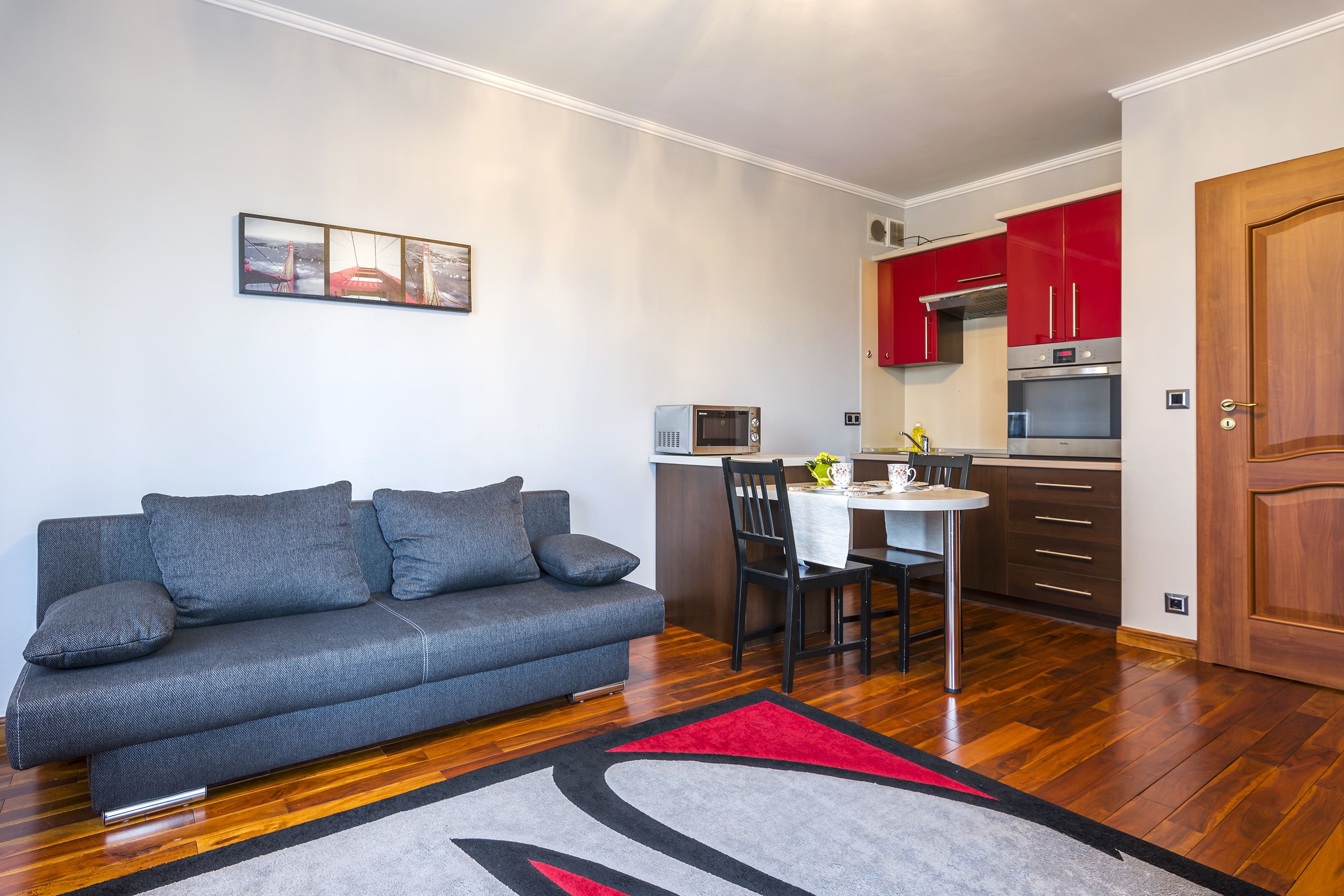 A compact living space with a sofa, a dining table, and a kitchenette.