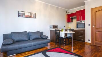 A compact living space with a sofa, a dining table, and a kitchenette.