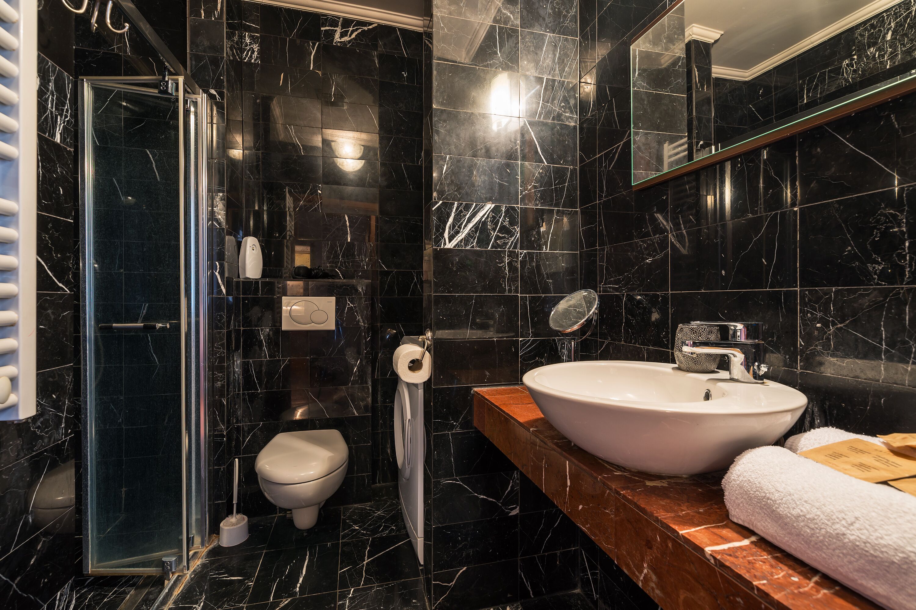 Un baño moderno con cabina de ducha de vidrio, inodoro blanco y un lavamanos grande con encimera de madera.