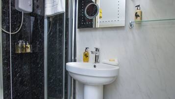 A modern bathroom with a glass-enclosed shower, a pedestal sink, and a toilet.