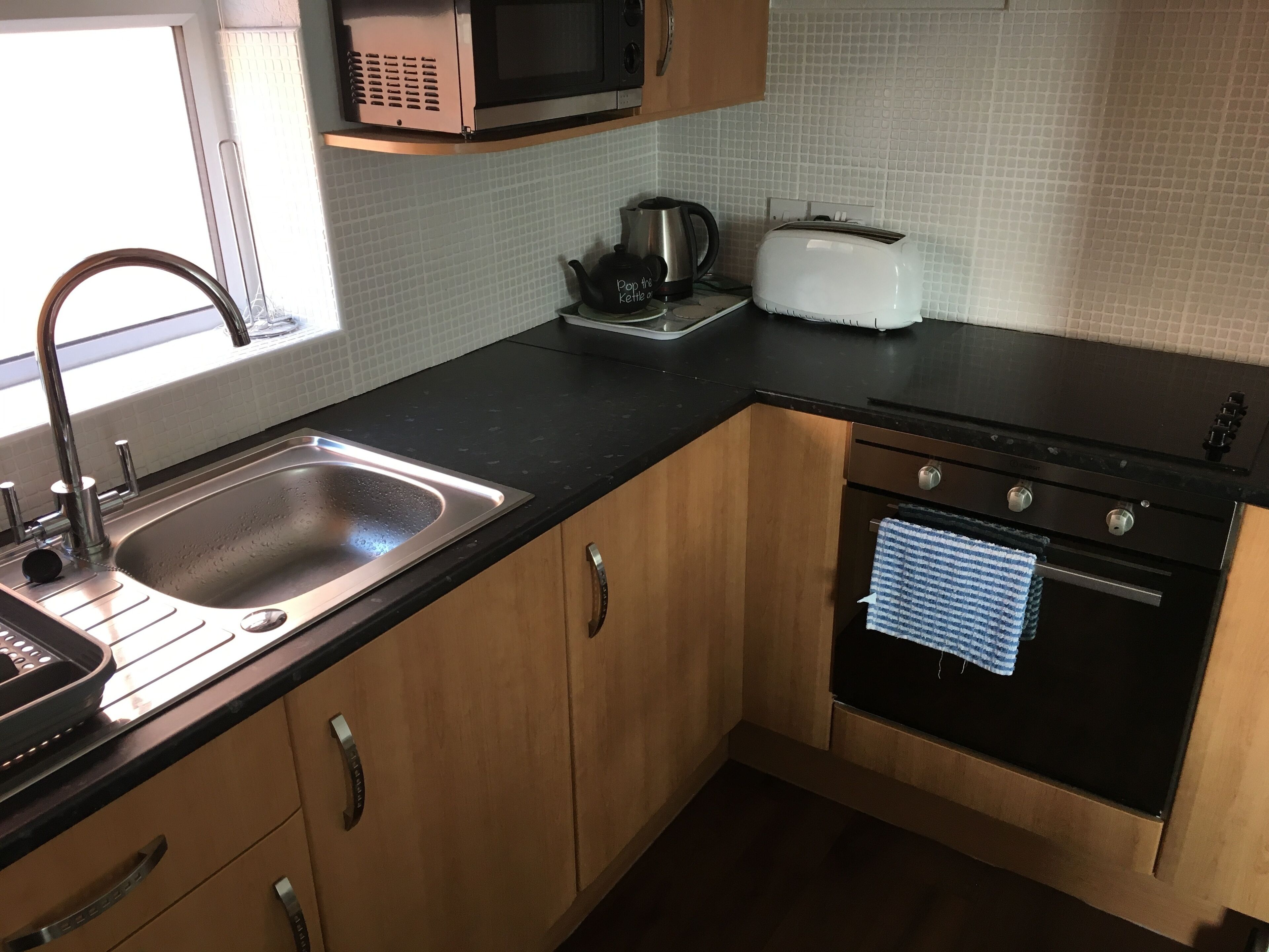 A kitchen with a sink, a microwave, a toaster, and an oven.