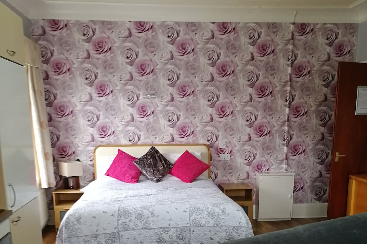 Une chambre à coucher comprenant un lit, une table de chevet, une armoire et un radiateur.