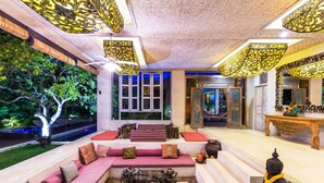A modern interior with a seating area, a Buddha statue, and a view of greenery outside. - BoHo Bingin Beach (Pecatu)