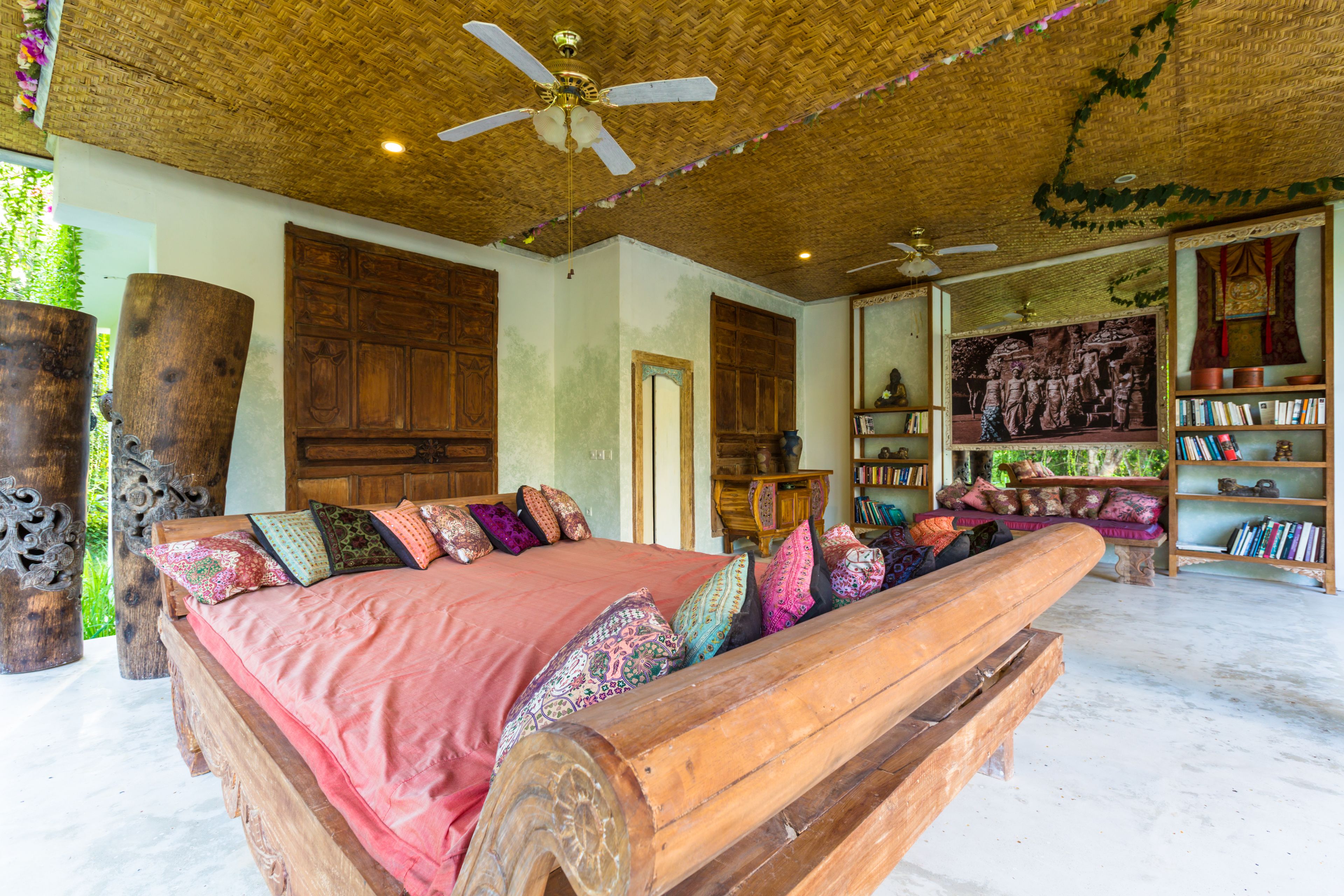 A spacious room with a large bed, wooden furniture, and a ceiling fan.