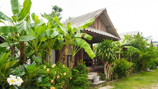 A wooden house with a sloped roof, surrounded by lush banana trees and flowering plants. - Weekender Bungalow (Koh Samui)