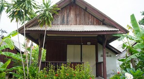Uma casa de madeira com telhado de metal corrugado, varanda e porta com o número 10.