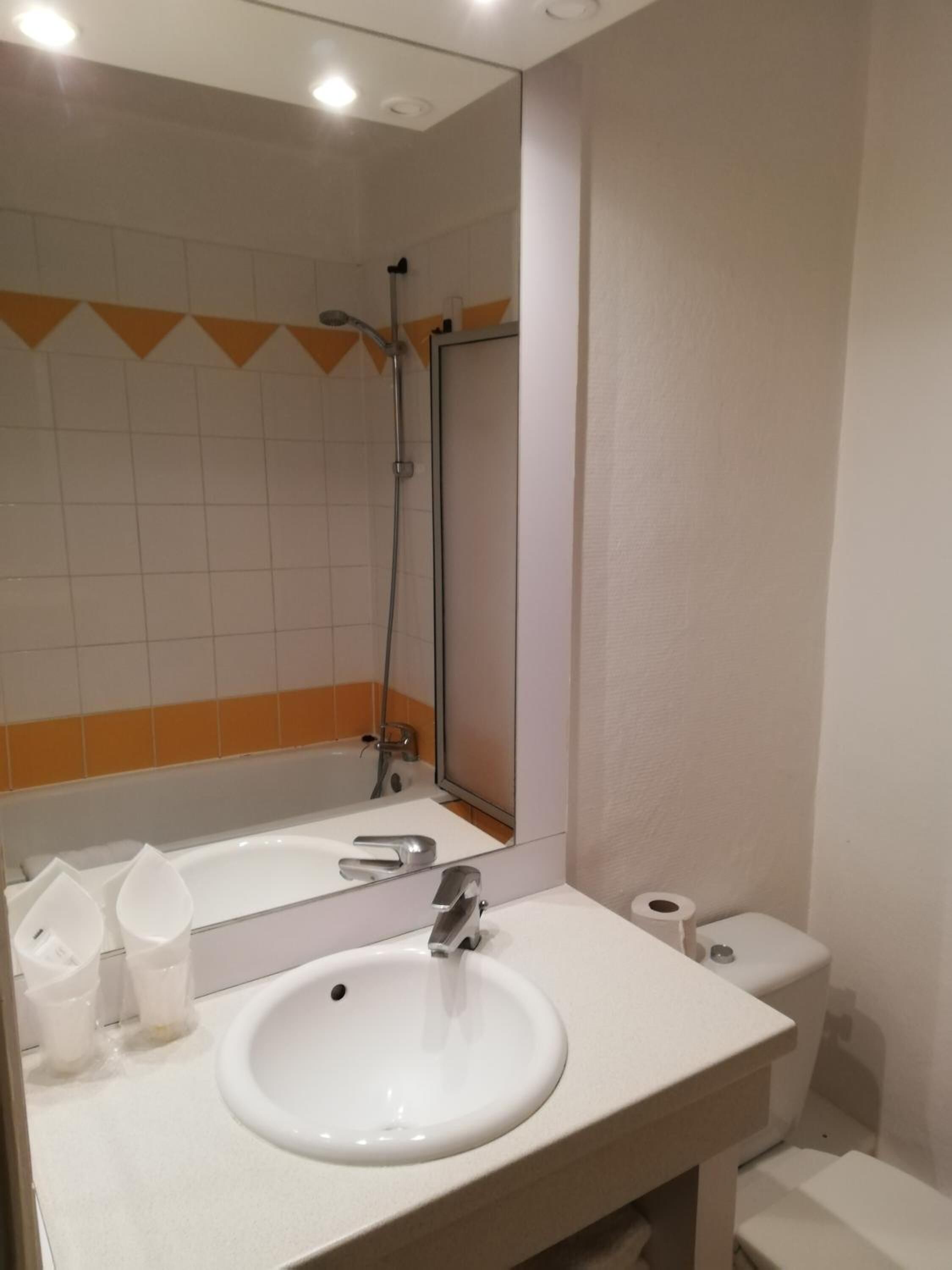 A bathroom with a white sink, a mirror, a shower, and a toilet.