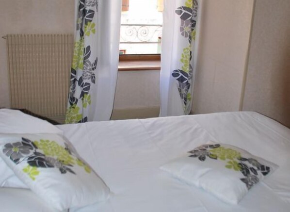A hotel room with a bed, floral curtains, and a window with a view of a balcony. - Hôtel la Poularde (Louhans)