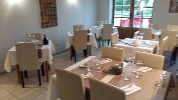 A dining area with multiple tables set for service, chairs, and a large window with a view of the outside.