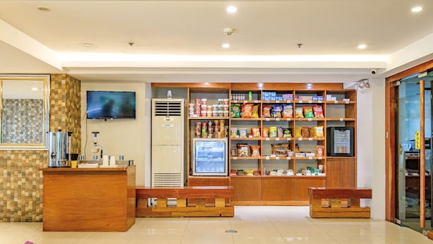 A hotel lobby with a reception desk, a television mounted on the wall, and a variety of snacks and beverages on shelves. - MySpace Hotel at BGC (Taguig)