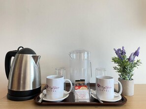 A hotel breakfast setup with a kettle, two mugs, a pitcher, and a tray with sugar packets. - MySpace Hotel at BGC (Taguig)