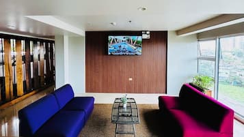 Een moderne lobby met een blauwe bank, een roze bank en een bijzettafeltje met planten.