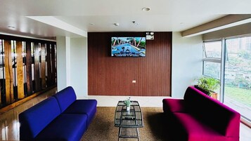A modern lobby with a blue sofa, a pink sofa, and a coffee table with plants.